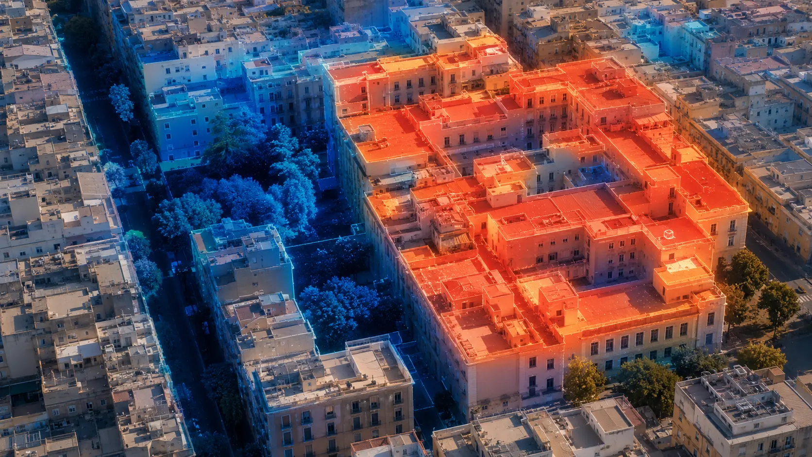 Aerial thermal visualization of a dense urban block, with one hot city block rendered in orange against cooler blue surroundings